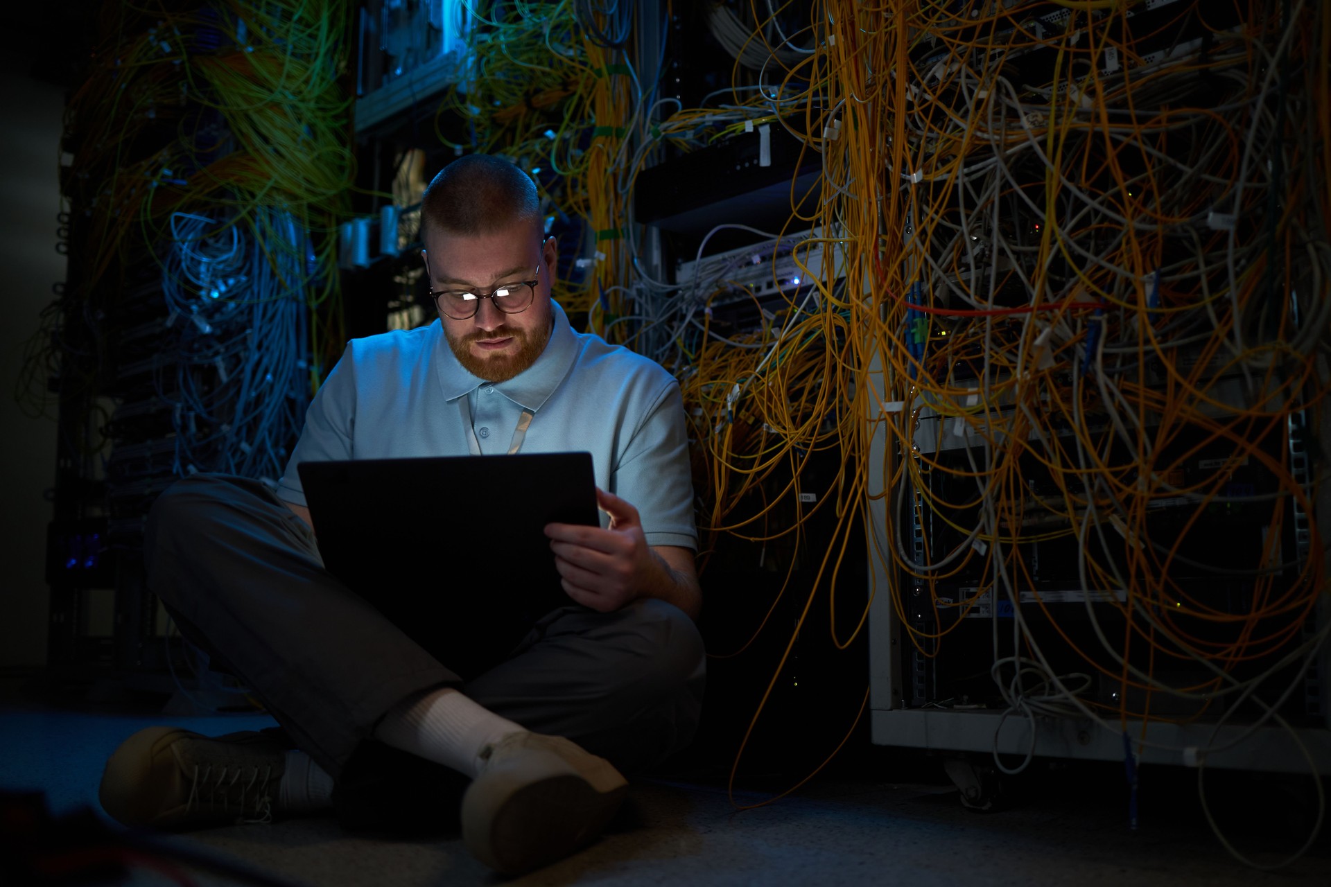 Person Sitting and Working with Laptop in Data Center